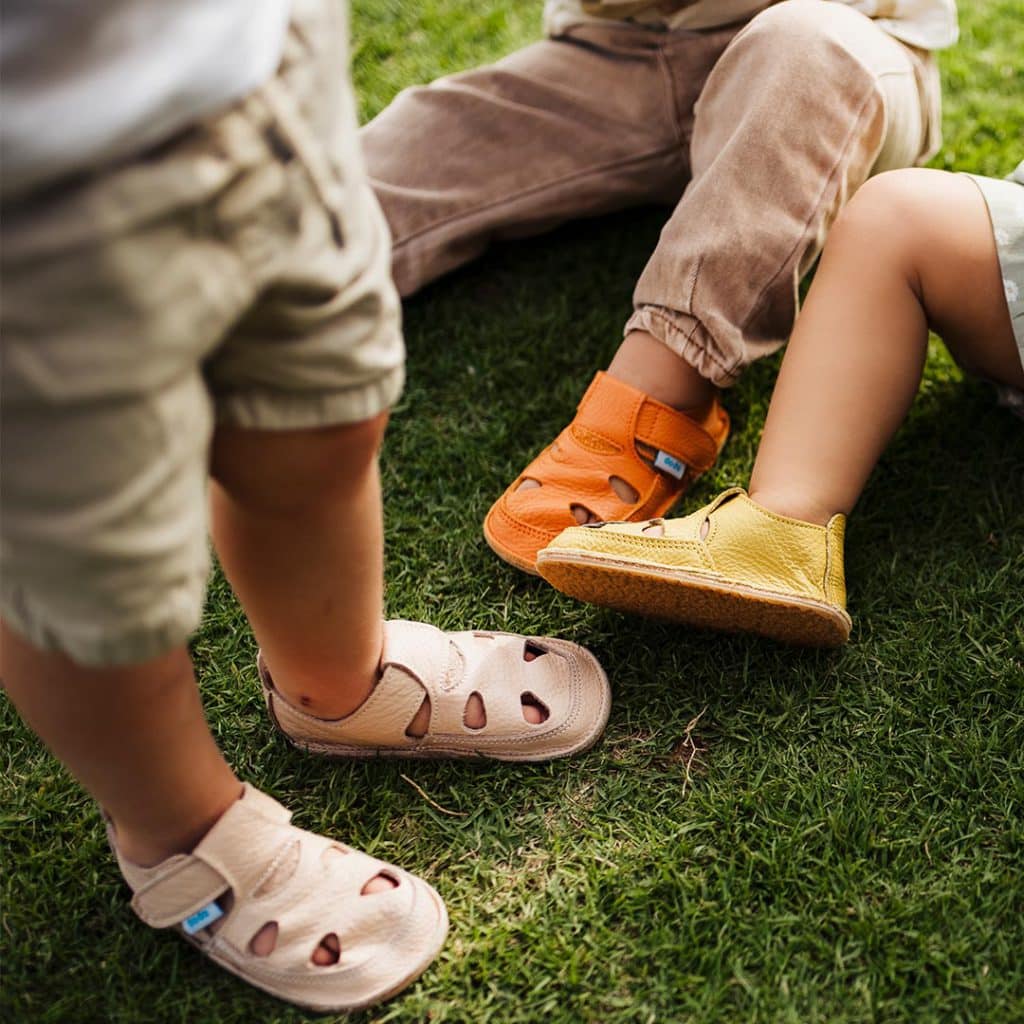 Toddlers feet on the grass in barefoot shoes.